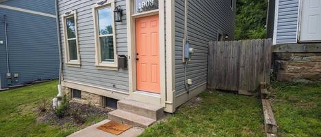 A house with a number '1903' on the front door, a small front yard, and a wooden fence.