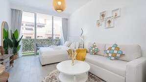 A modern living room with a sofa, a coffee table, and a dining area. - Brand New & Modern Studio JVC (Dubai)