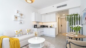 A modern living room with a sofa, coffee table, and a dining area with chairs and a table. - Brand New & Modern Studio JVC (Dubai)