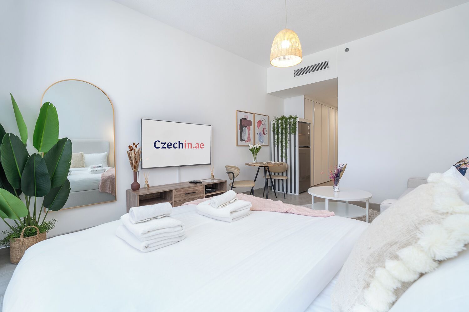 Ein modernes Hotelzimmer mit einem großen Bett, einem Fernseher, einem Schreibtisch und einem Essbereich.