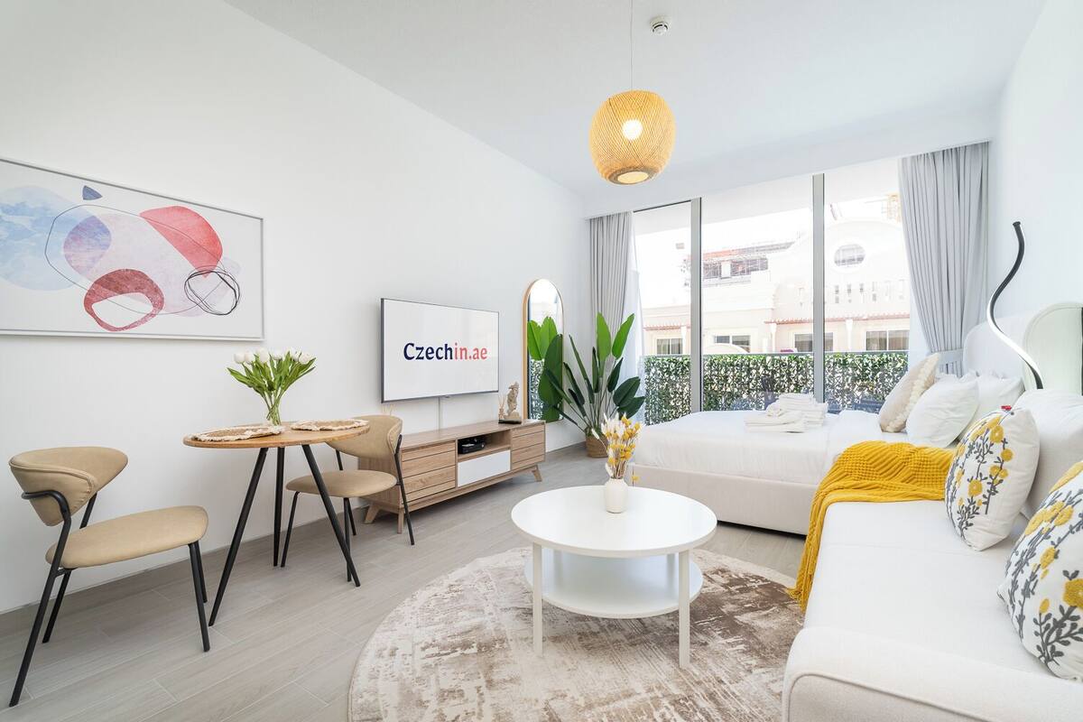 A modern living room with a sofa, a coffee table, a TV, and a dining area.