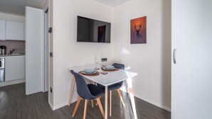 Un comedor moderno con una mesa blanca, sillas oscuras y un cuadro de un ciervo.
