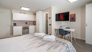 Una habitación de hotel moderna con cama, escritorio, televisión y kitchenette.