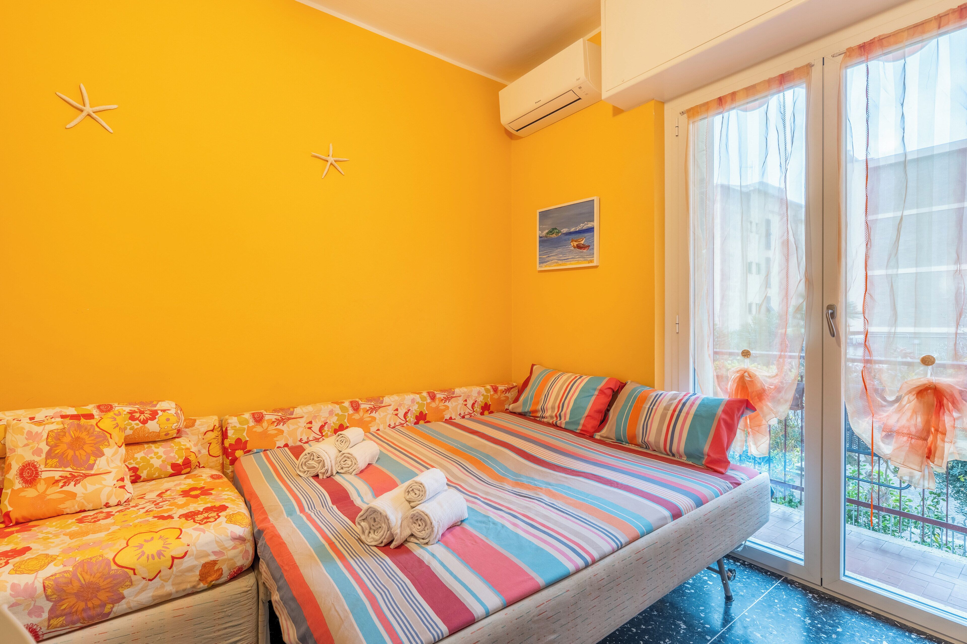 A room with a bed, a sofa, and a window with curtains.