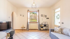 Una sala de estar moderna con televisor, sofá, mesa de comedor y vista por la ventana.