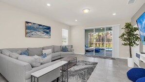 A modern living room with a grey sectional sofa, a coffee table, and a large painting on the wall.