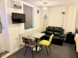 Relax in a compact room with a flat-screen TV, comfortable sofa, and a small table for work or dining.