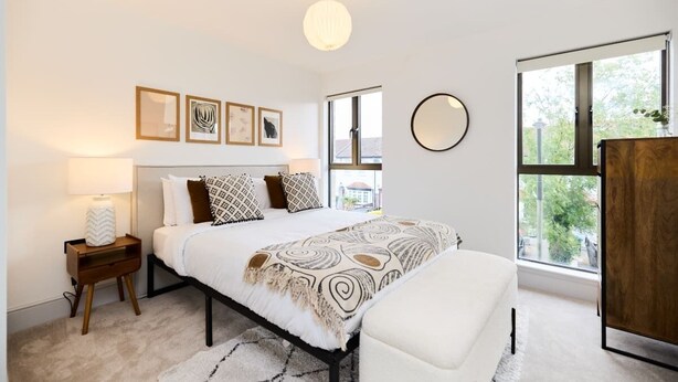 A bedroom with a bed, bedside tables, a mirror, and a window with a view of trees. - The South Wimbledon Hideout - Fancy 1bdr Flat With Balcony (London)