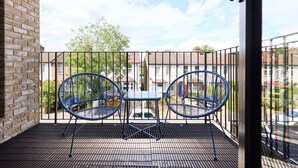 A balcony with two blue chairs and a small table, overlooking a residential area with houses and a tree. - The South Wimbledon Hideout - Fancy 1bdr Flat With Balcony (London)