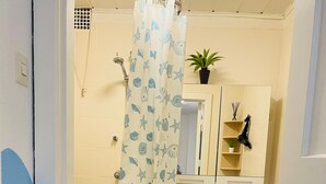A bathroom with a toilet, sink, shower, and a mirror above the sink.