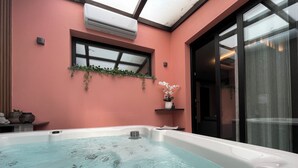 Ein Whirlpool mit freiem Blick auf das Wasser, ein Fenster mit Aussicht und ein Blumentopf an der Wand.