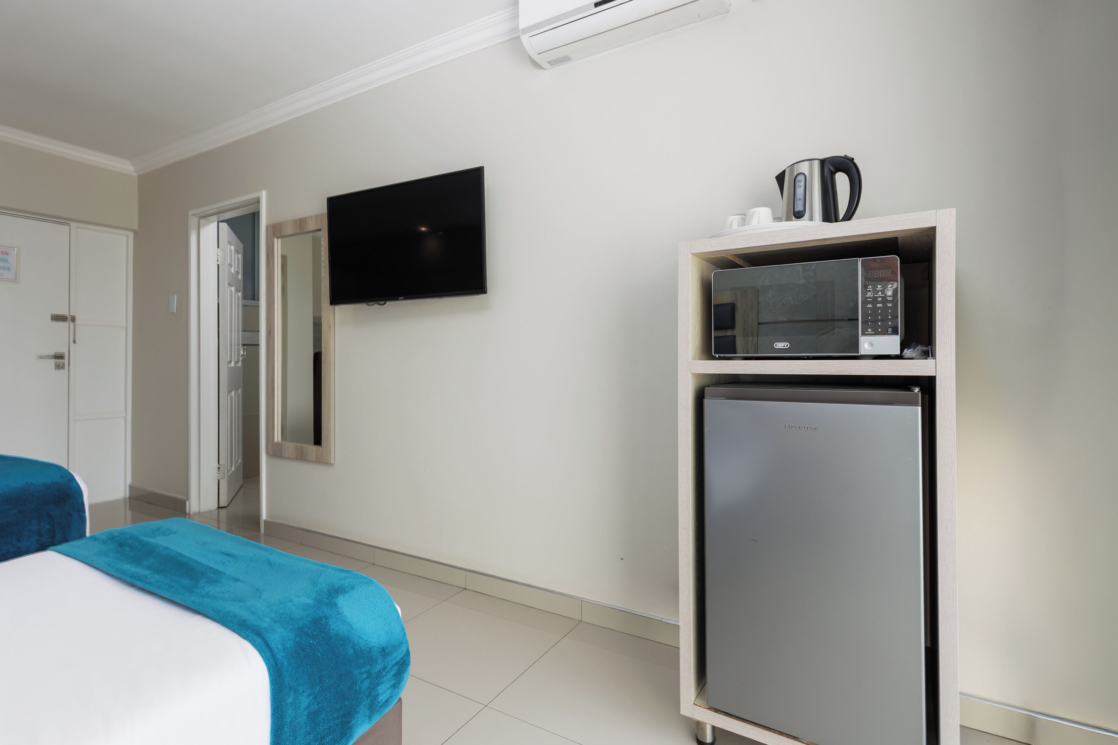 Una habitación de hotel con una cama, televisor, microondas y refrigerador.