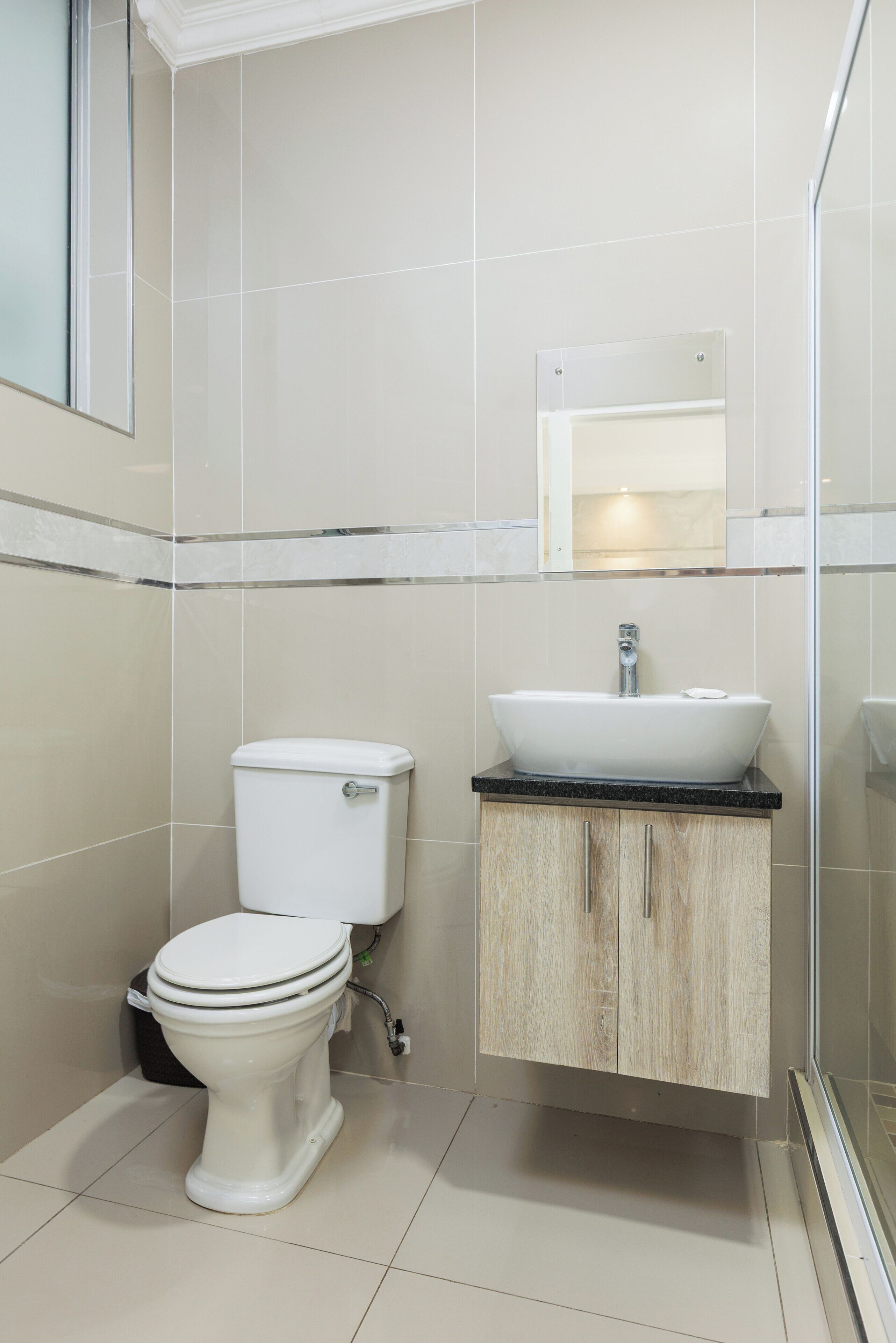 A modern bathroom with a toilet, sink, and mirror.