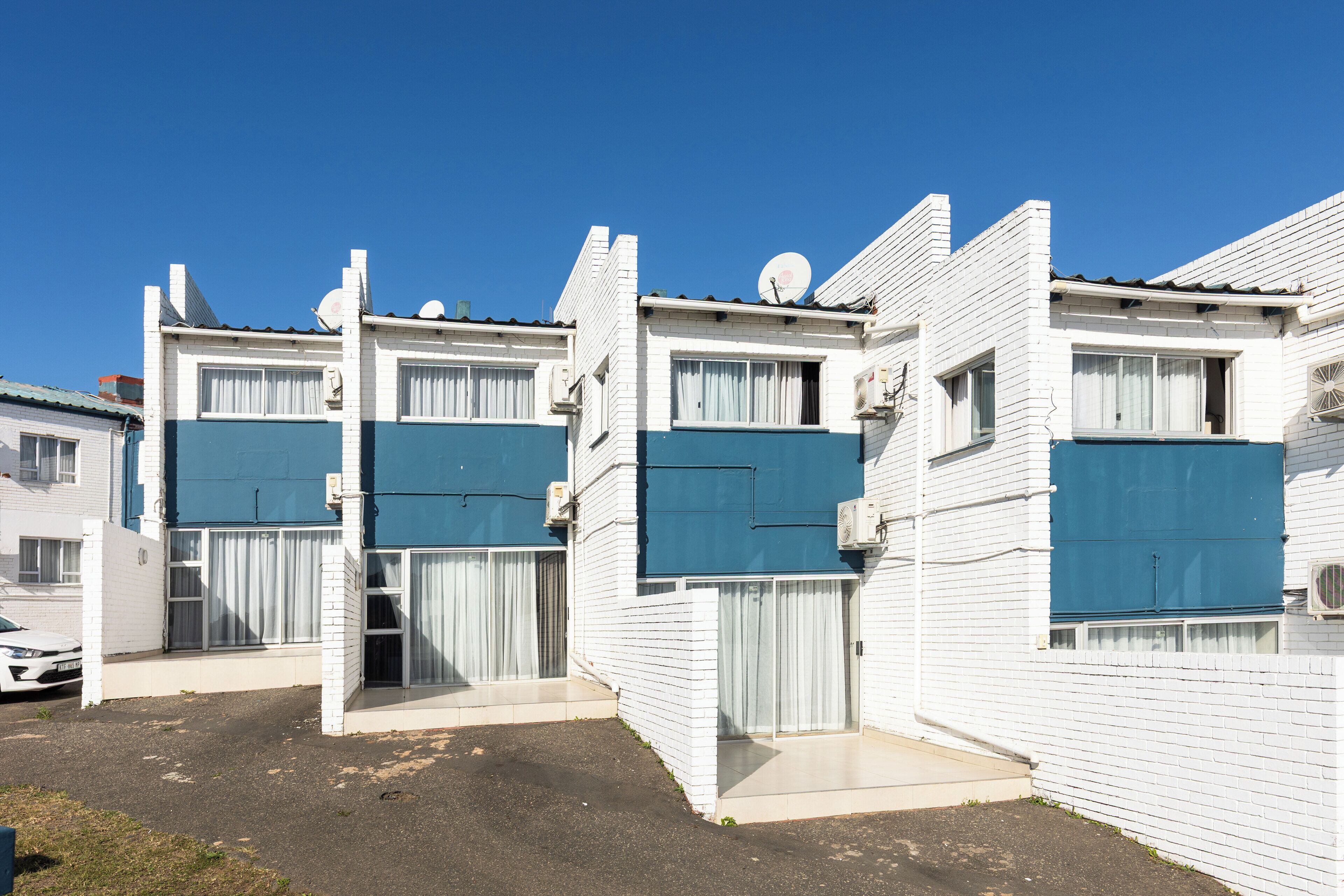 A row of white buildings with blue awnings and satellite dishes on the roof.