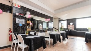 Un comedor de hotel con manteles negros, sillas blancas y un cartel que indica 'Strictly No Smoking'.
