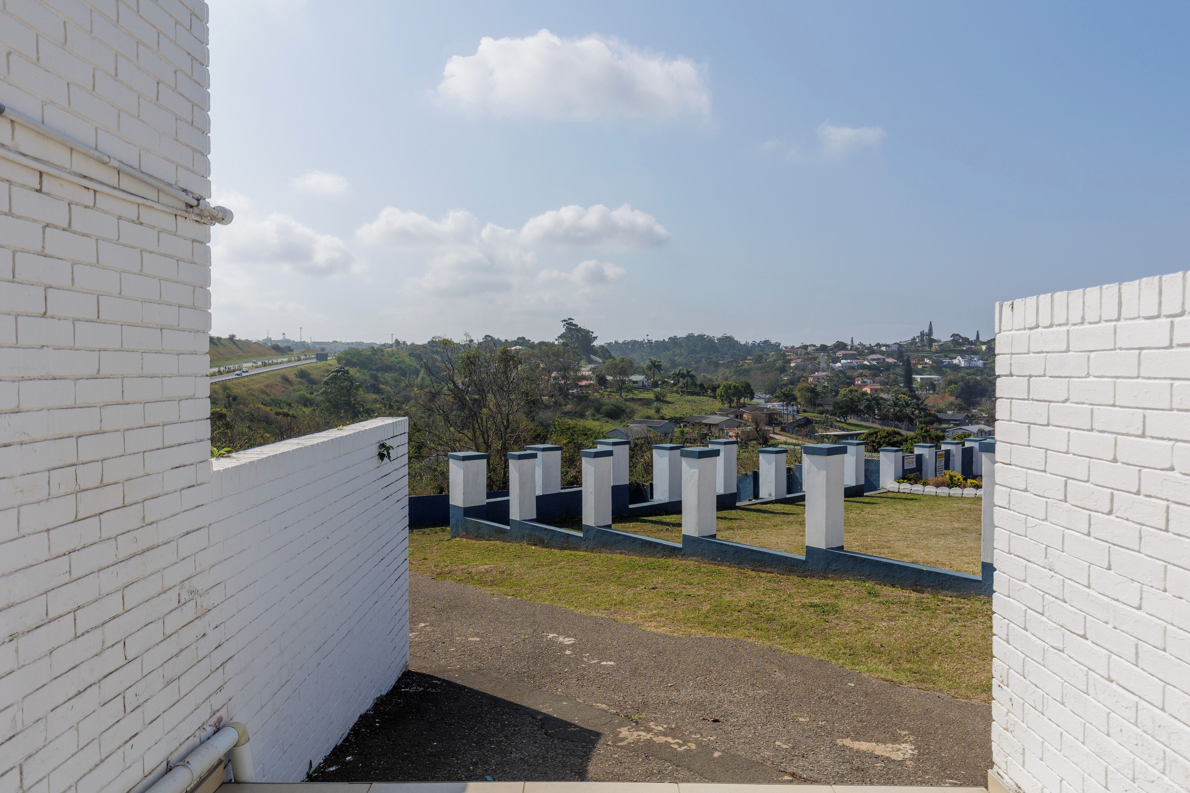 A view of a cemetery with white brick walls and a clear sky.