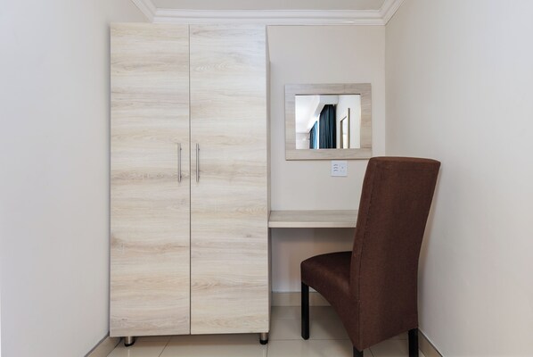 A room with a wardrobe, a desk, and a chair. - Bayside Taj Hotel (Port Shepstone)