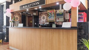 Un mostrador de recepción con un cartel que dice "RECEPTION", un cuadro enmarcado de Nelson Mandela y una pizarra de menú.