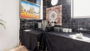 Una habitación con una mesa negra, una máquina de café y un cuadro en la pared.