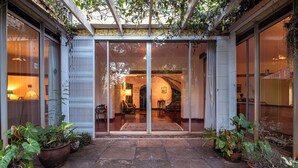 Entrada com porta de vidro para um edifício com área de pátio revestida em azulejos.