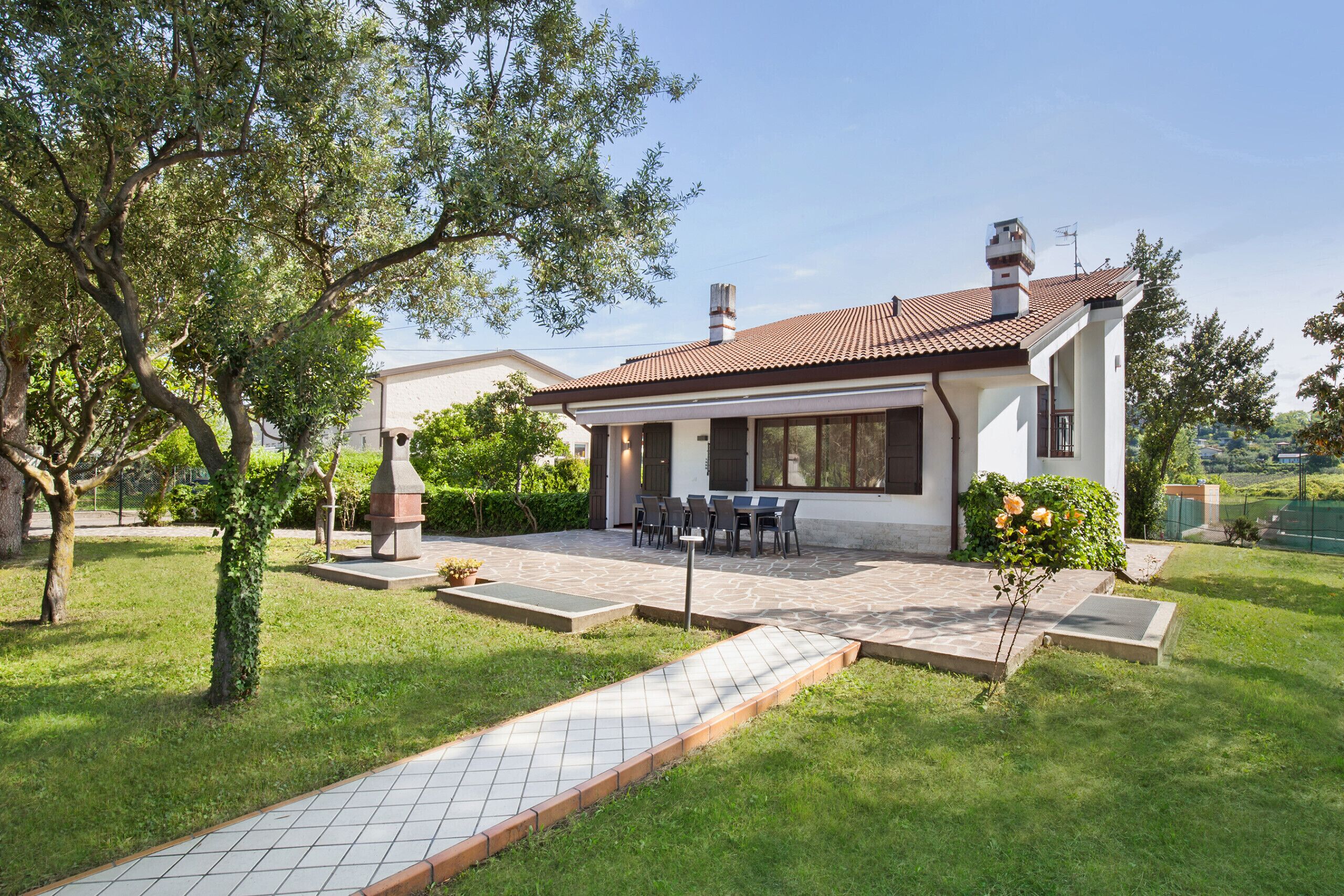 Una casa con patio, mobili da esterno e giardino.