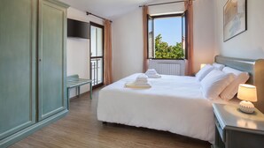 A hotel room with a bed, a desk, a wardrobe, and a window with a view. - Villa Delle Coste With Pool (Lazise)