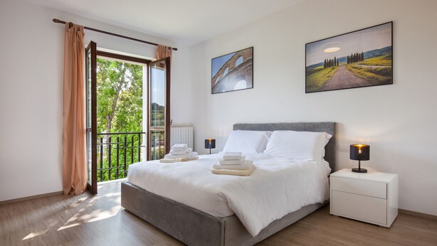 A modern bedroom with a large bed, a nightstand, and two paintings on the wall. - Villa Delle Coste With Pool (Lazise)