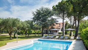 A swimming pool with lounge chairs and a building in the background. - Villa Delle Coste With Pool (Lazise)