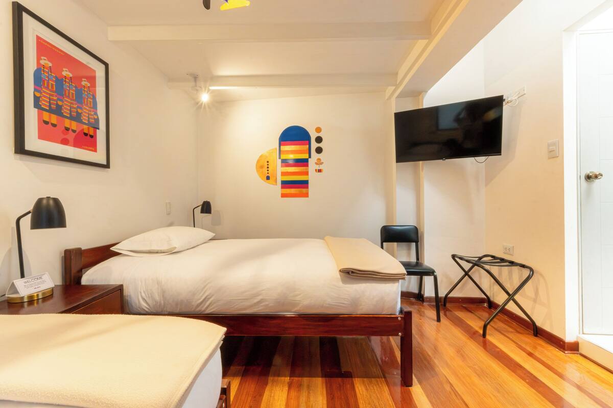 Una habitación de hotel con una cama, un televisor, un escritorio y una silla.