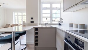 Une cuisine moderne dotée d’un îlot central, d’un four encastré et d’une fenêtre laissant entrer la lumière naturelle.