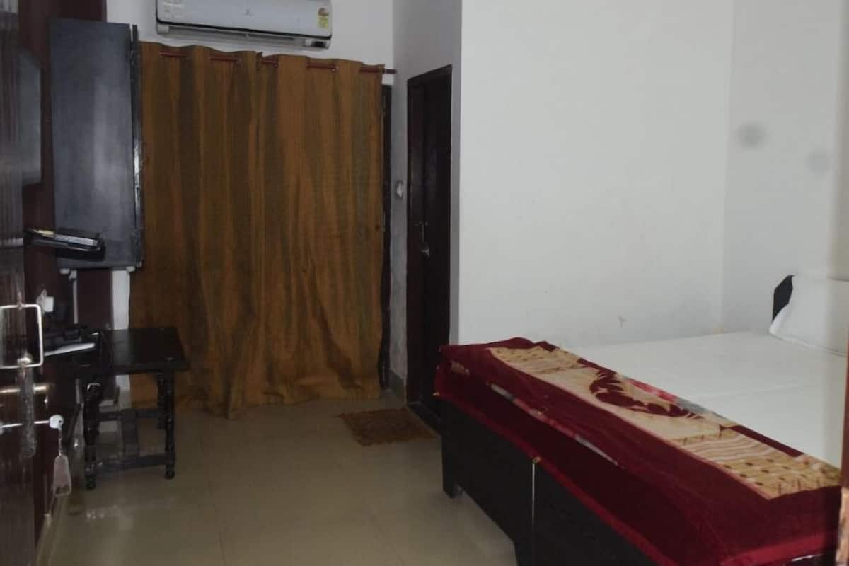 Un dormitorio con una cama, un escritorio, una silla, un armario y un equipo de aire acondicionado.