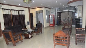 A spacious living room with a sofa, armchairs, a coffee table, and a fireplace. - Ali Baba Guest House (Varanasi)
