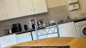 A kitchen with white cabinets, a coffee maker, a blender, and a washing machine. - Stylish 1-bed Apt - Sleeps 4 - Parking - Wifi (Manchester)