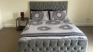 A bed with a tufted headboard and a patterned bedspread. - Stylish 1-bed Apt - Sleeps 4 - Parking - Wifi (Manchester)