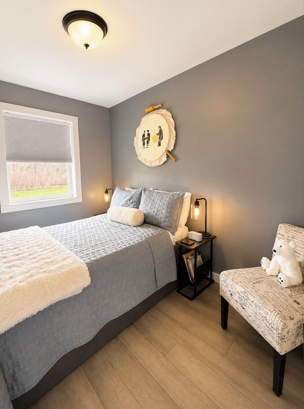 Una camera da letto con un letto, un comodino, una lampada, una sedia e un elemento decorativo al muro.