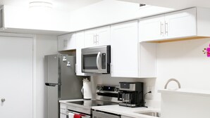 Een moderne keuken met witte kastjes, roestvrijstalen apparatuur en een houten vloer.