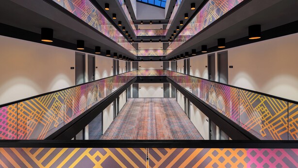 A modern interior with a central escalator, glass ceiling, and patterned walls. - Ginger Udaipur Shastri Circle (Udaipur)