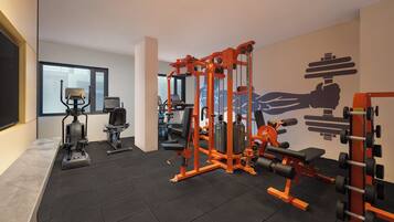 A gym with various exercise equipment, including a bench press, a squat rack, and a treadmill.