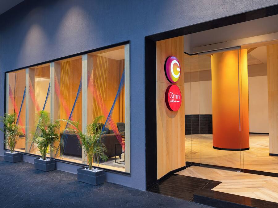 A modern hotel entrance with large windows, a reception desk, and a sign for 'Ginn'.