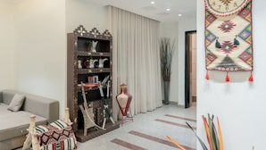 A modern living room with a sofa, a decorative bookshelf, a hanging tapestry, and a tall vase.