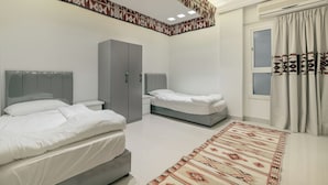 A modern bedroom with two beds, a wardrobe, and a patterned rug.