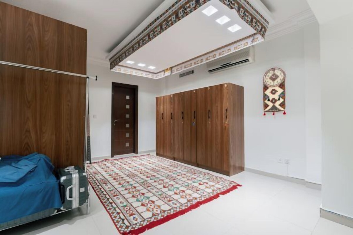Una habitació amb llit, armari i una alfombra amb dibuixos.