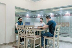 A meeting room with a glass partition, wooden chairs, and a laptop on the table. - Sands Inn Hostel (Riyadh)
