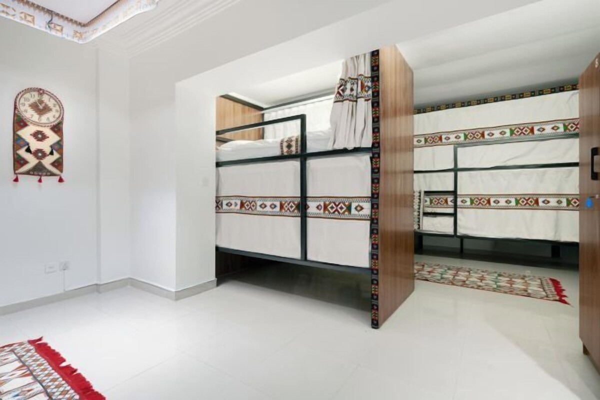 Une chambre avec des lits superposés, un tapis à motifs et un élément décoratif mural.