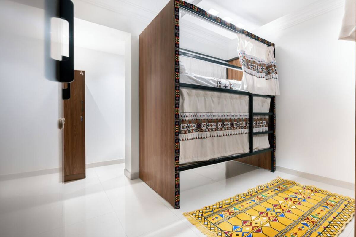 Una habitació moderna amb un llit superposat, una porta de fusta i una catifes amb dibuixos.