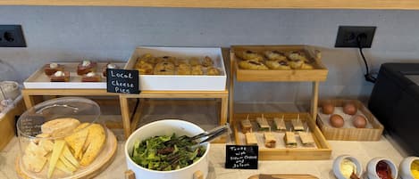 Een etalage met gemarkeerde sauzen, diverse gebakjes, belegde broodjes en een saladekom.