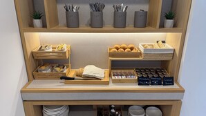 Una barra de desayuno ordenada con espacio de almacenamiento de madera para pan, pasteles y condimentos.