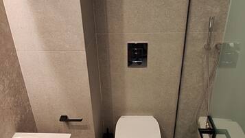 A modern bathroom with a white toilet, a glass-enclosed shower, and a sink with a mirror.