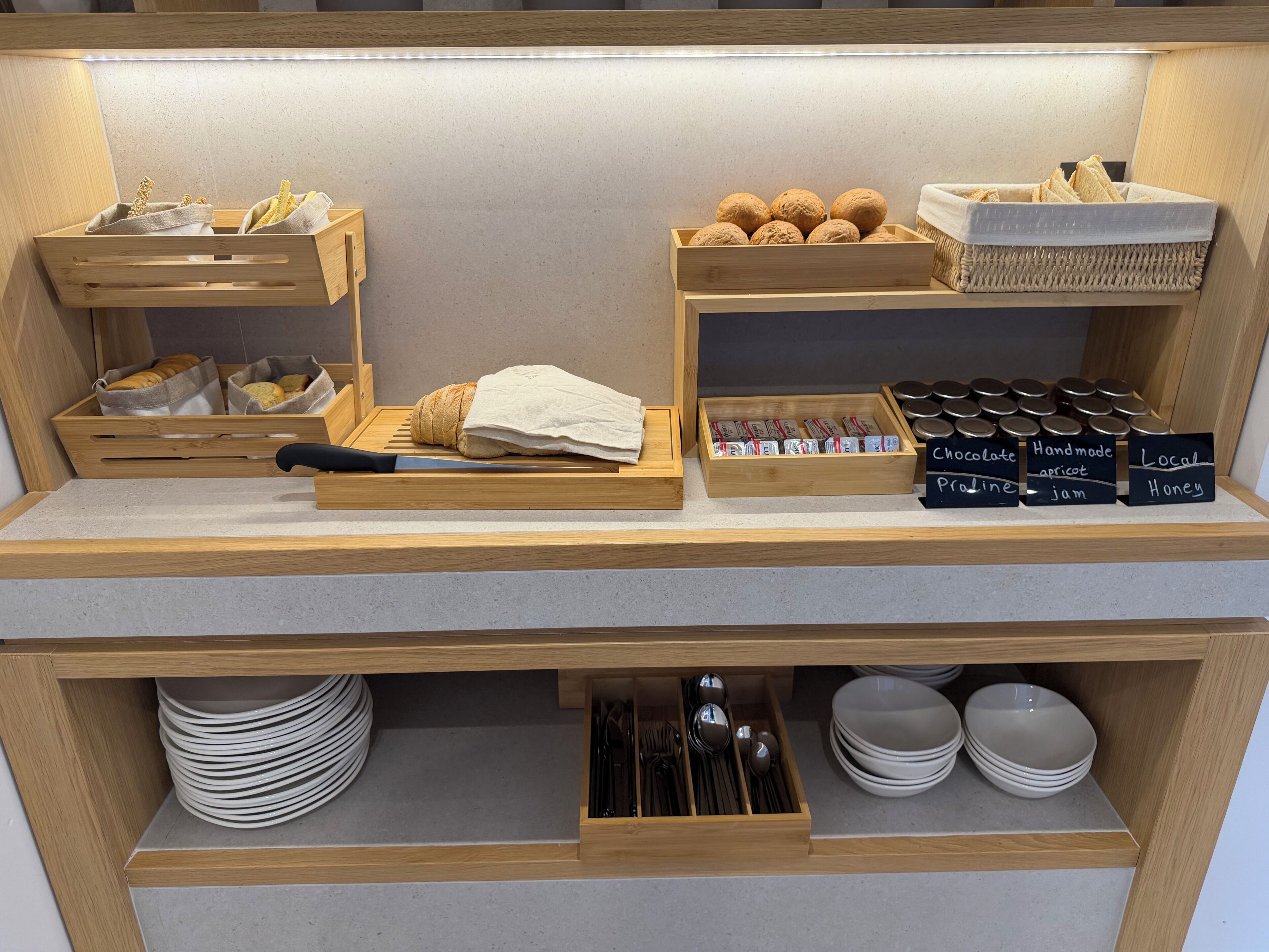 Un bar pour le petit-déjeuner doté de rangements en bois pour le pain, les viennoiseries et les condiments.