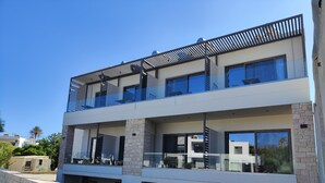 Un moderno edificio residencial de dos pisos con techo plano, ventanas amplias y fachada de piedra.